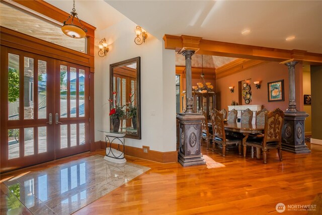 foyer featuring wood finished floors, french doors, and ornate columns