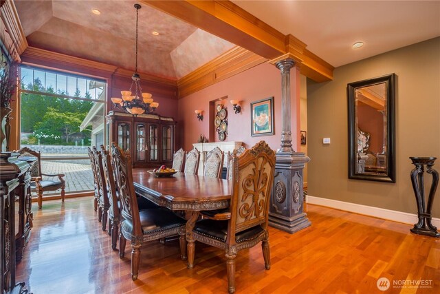 dining area with baseboards, decorative columns, an inviting chandelier, and wood finished floors