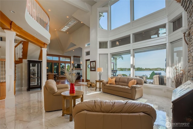 living room with a stone fireplace, a high ceiling, marble finish floor, and ornate columns