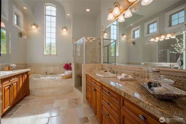 bathroom with vanity, a high ceiling, stone tile flooring, a shower stall, and a garden tub