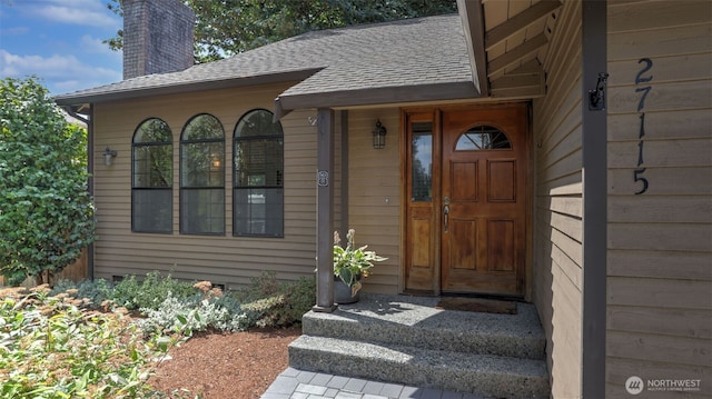 property entrance with roof with shingles and a chimney