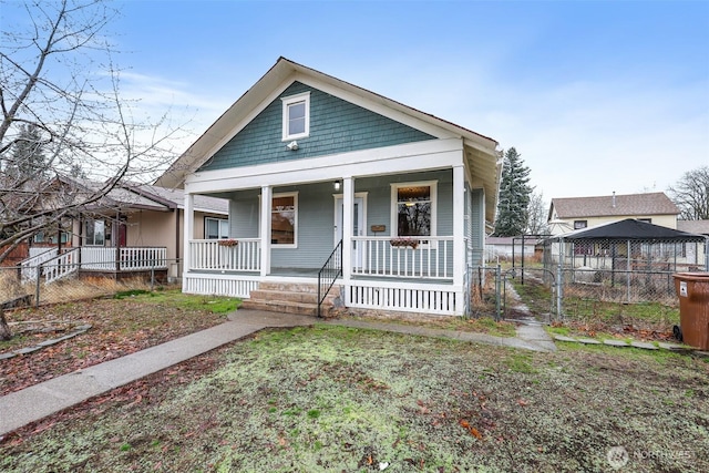 bungalow-style house featuring a gate, a porch, and fence