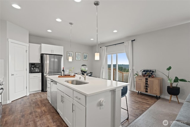 kitchen featuring decorative light fixtures, an island with sink, appliances with stainless steel finishes, white cabinets, and a sink