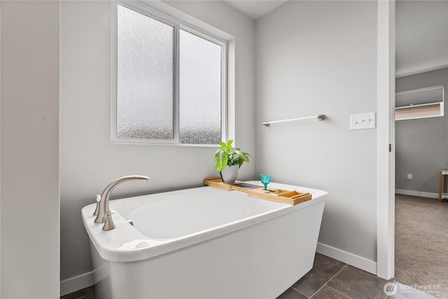 bathroom featuring a soaking tub, plenty of natural light, and baseboards