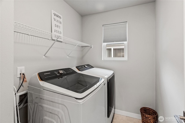 clothes washing area with laundry area, washing machine and dryer, and baseboards