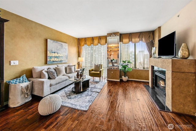 living room featuring baseboards, a glass covered fireplace, and hardwood / wood-style flooring