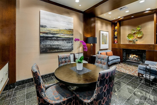 dining area featuring recessed lighting, visible vents, a warm lit fireplace, and granite finish floor