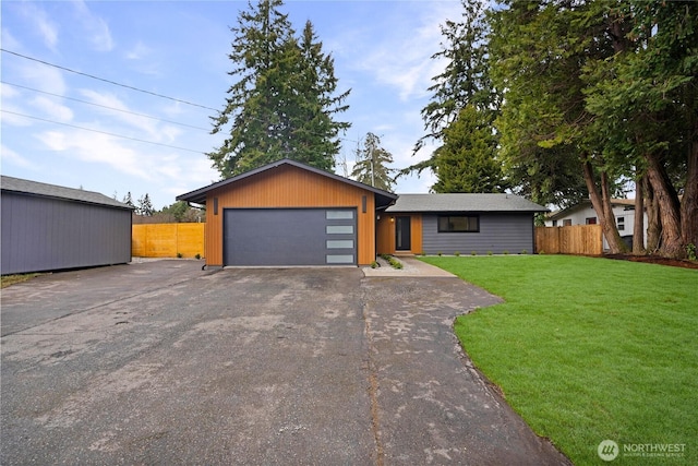 mid-century modern home with a front yard, fence, a garage, and driveway