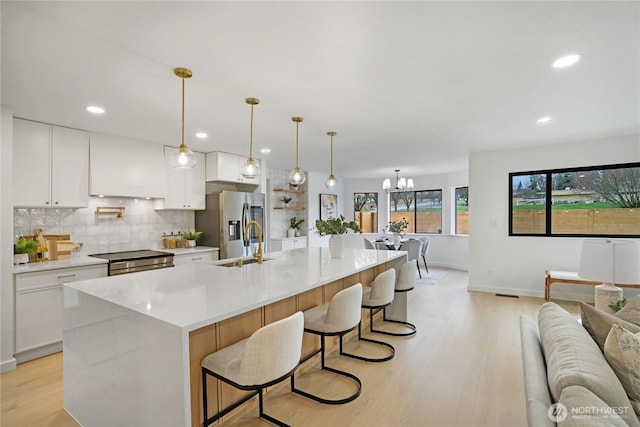 kitchen with tasteful backsplash, open floor plan, light countertops, appliances with stainless steel finishes, and a sink