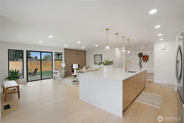 kitchen featuring modern cabinets, a sink, open floor plan, recessed lighting, and light wood-style floors