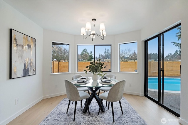 dining room with baseboards, light wood-type flooring, and a chandelier