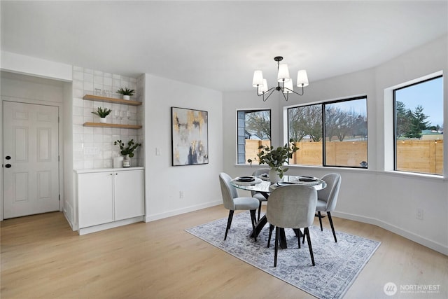 dining space with a notable chandelier, light wood-style floors, and baseboards