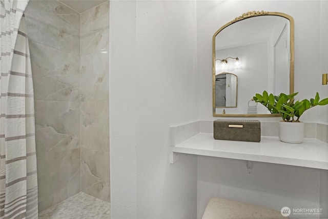 full bath featuring tiled shower and vanity