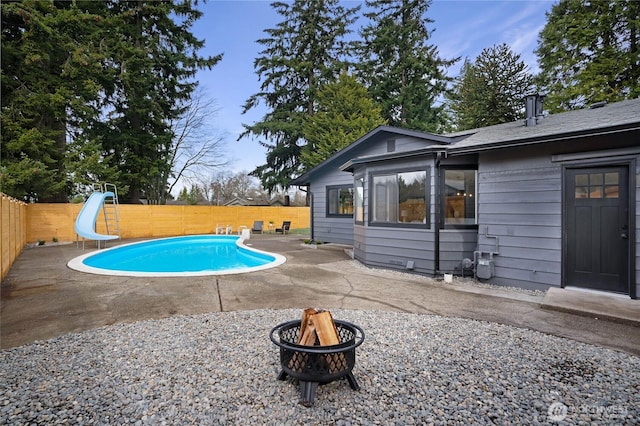 view of pool with a fenced in pool, a water slide, an outdoor fire pit, a fenced backyard, and a patio area