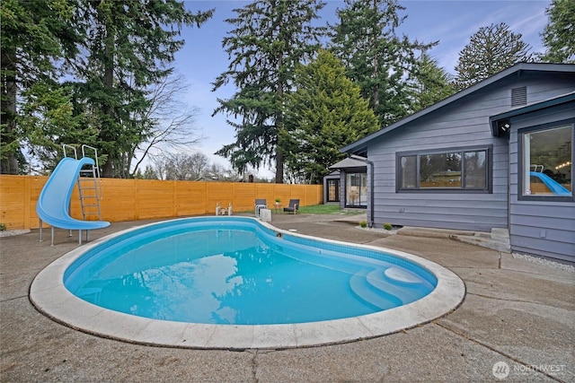 view of pool with a patio, a fenced backyard, a fenced in pool, and a water slide