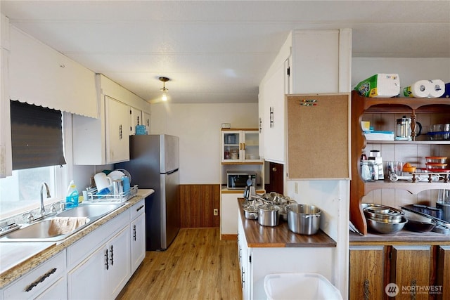 kitchen with white cabinetry, light wood finished floors, appliances with stainless steel finishes, and a sink