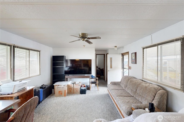 living area with a wealth of natural light, carpet, a ceiling fan, and a textured ceiling