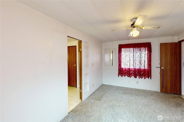 spare room featuring a ceiling fan, light colored carpet, and light floors