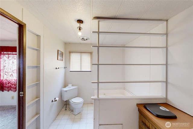 bathroom featuring tile patterned floors, toilet, and a textured ceiling