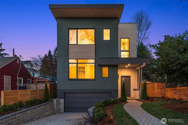 contemporary home with an attached garage, fence, and driveway