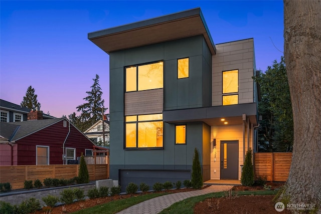 modern home featuring fence and board and batten siding