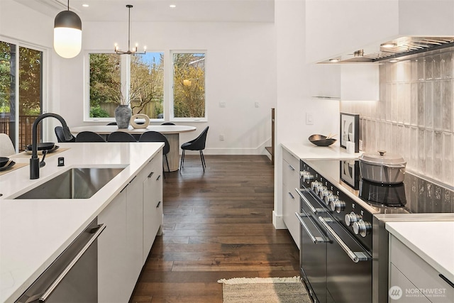 kitchen featuring a sink, plenty of natural light, wall chimney exhaust hood, range with two ovens, and dishwashing machine