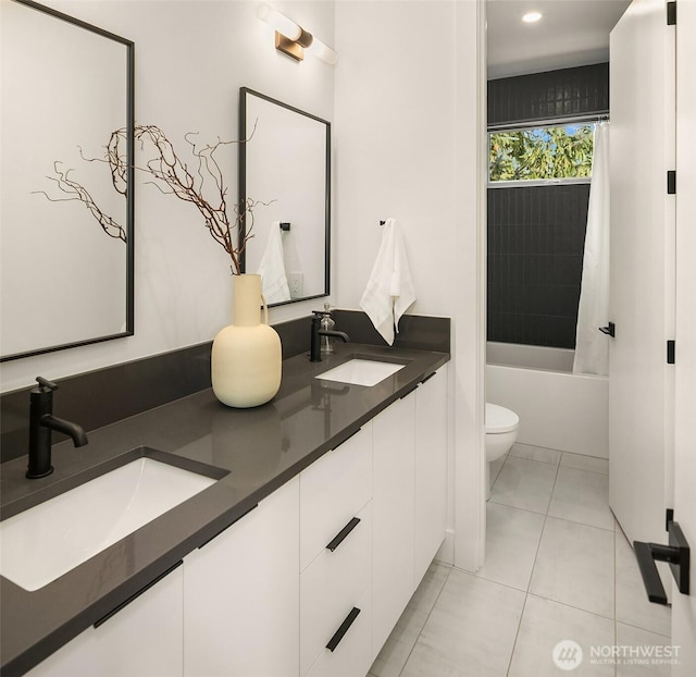 full bath with tile patterned flooring, double vanity, toilet, and a sink