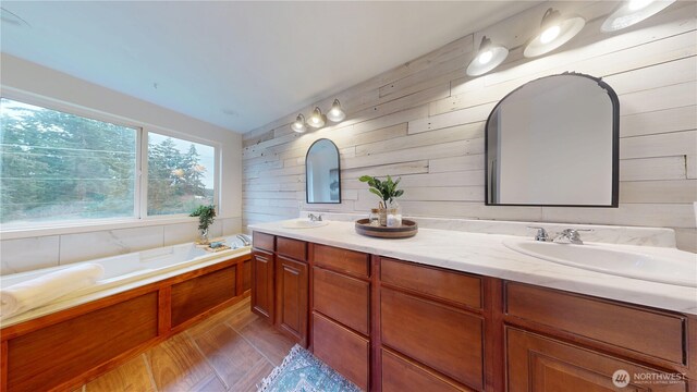 full bathroom with double vanity, a bath, and a sink