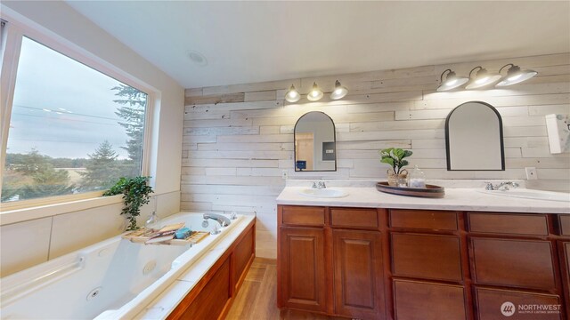 full bathroom featuring double vanity, a tub with jets, and a sink