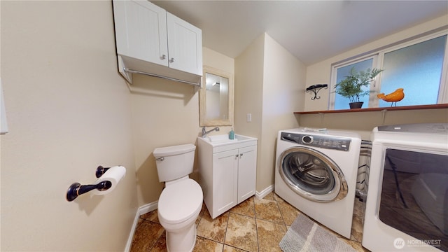 washroom with a sink, baseboards, laundry area, and washer and clothes dryer