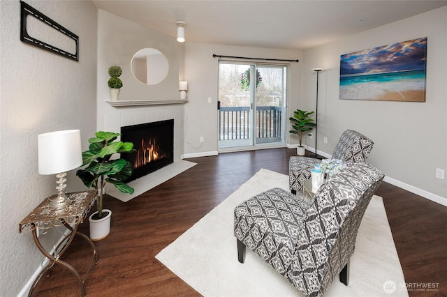 sitting room with a fireplace, baseboards, and wood finished floors