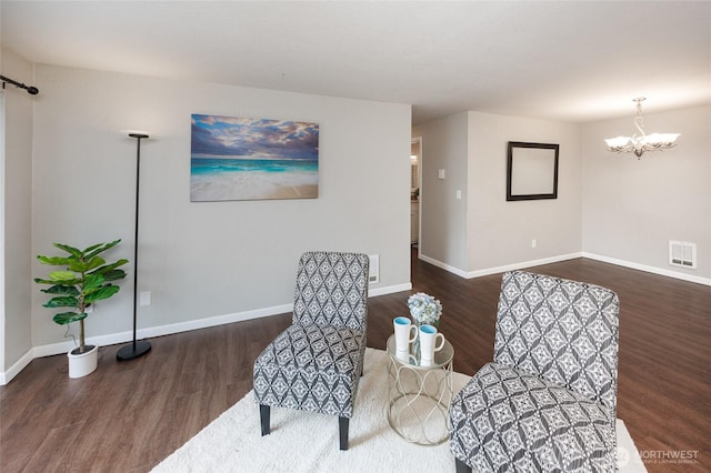 sitting room with a notable chandelier, visible vents, baseboards, and wood finished floors