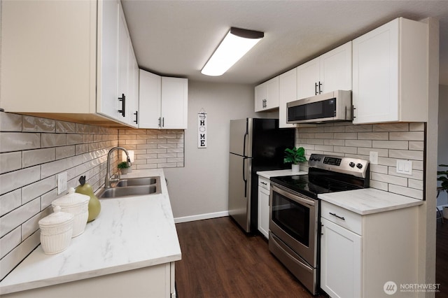 kitchen with a sink, dark wood-style floors, white cabinetry, appliances with stainless steel finishes, and decorative backsplash