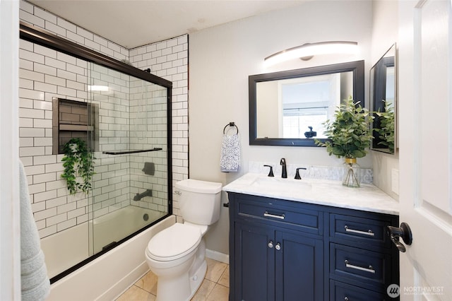 bathroom featuring baseboards, toilet, shower / bath combination with glass door, tile patterned floors, and vanity