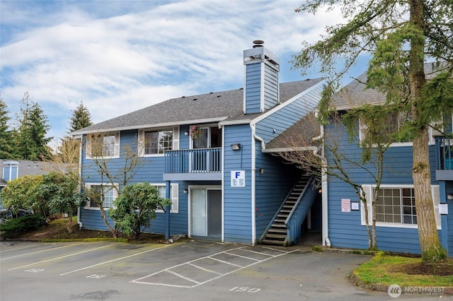 view of property featuring stairway and uncovered parking