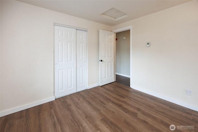 unfurnished bedroom featuring baseboards, attic access, and wood finished floors