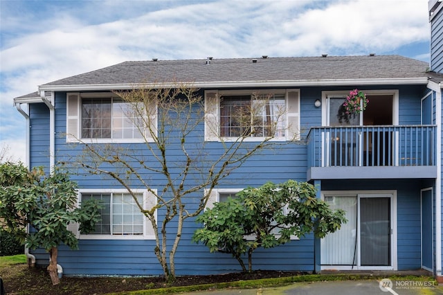 exterior space with a balcony and roof with shingles