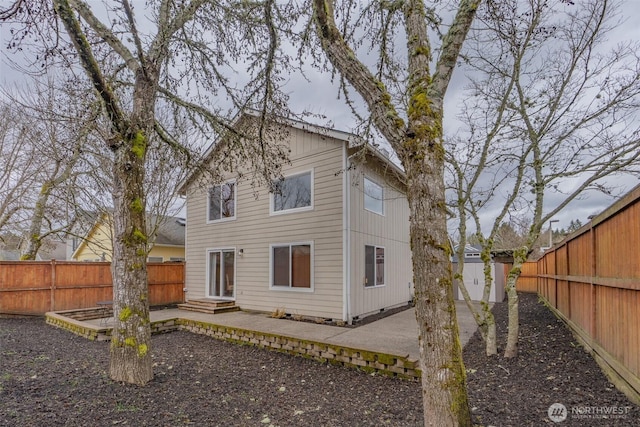 back of property with a fenced backyard, entry steps, and a patio