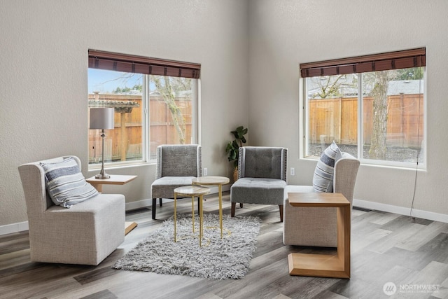 living area with wood finished floors, baseboards, and a textured wall