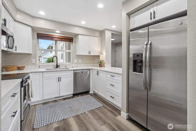 kitchen featuring a sink, dark wood-style floors, stainless steel appliances, white cabinets, and light countertops