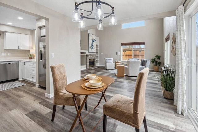 dining room featuring a notable chandelier, a glass covered fireplace, baseboards, and wood finished floors