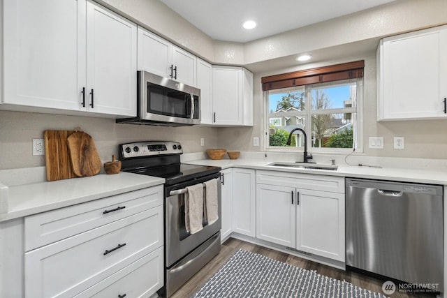 kitchen featuring a sink, dark wood-type flooring, light countertops, appliances with stainless steel finishes, and white cabinetry