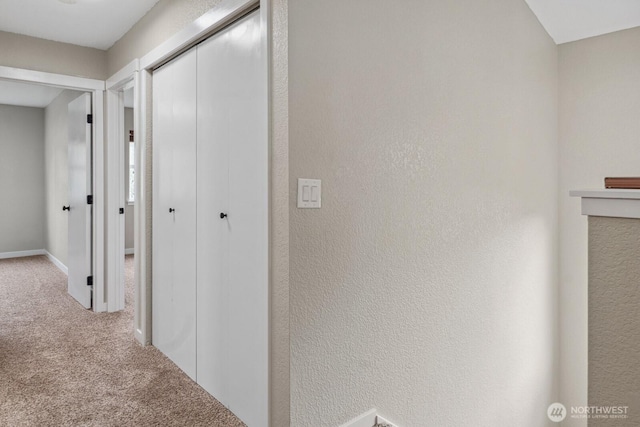 hall with carpet flooring and a textured wall