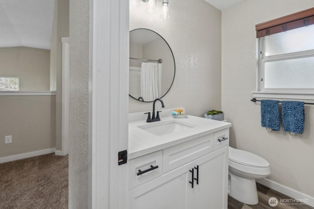 full bath featuring toilet, vanity, and baseboards