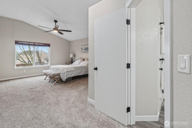 carpeted bedroom featuring ceiling fan, baseboards, lofted ceiling, and a textured wall