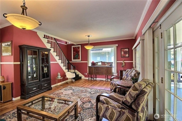 living area featuring crown molding, stairway, and wood finished floors