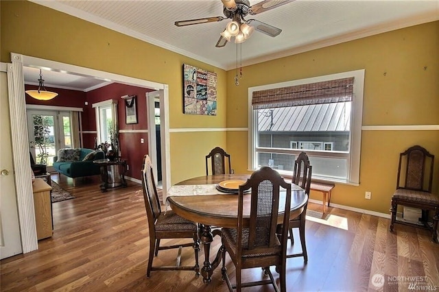 dining room with ornamental molding, ceiling fan, baseboards, and wood finished floors