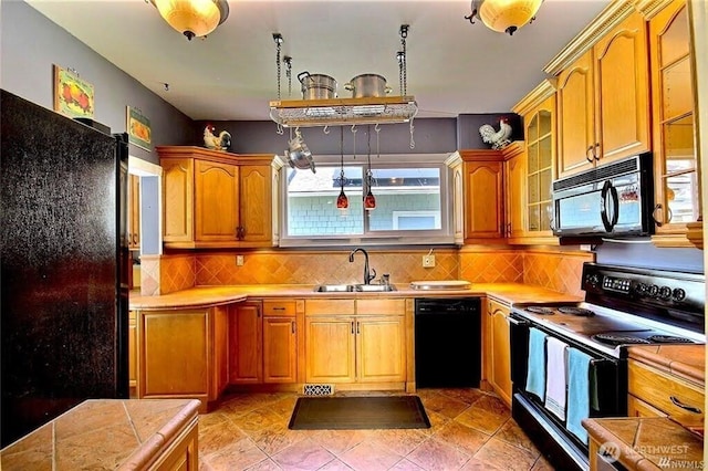 kitchen with a sink, glass insert cabinets, tasteful backsplash, and black appliances