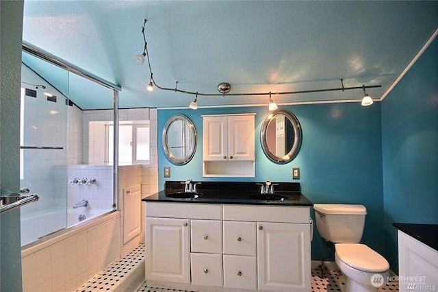 bathroom featuring double vanity, toilet, vaulted ceiling, and a sink