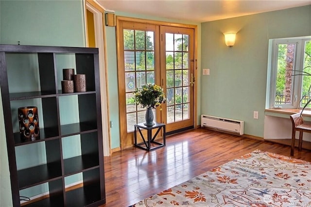 doorway featuring baseboard heating, a healthy amount of sunlight, and wood finished floors